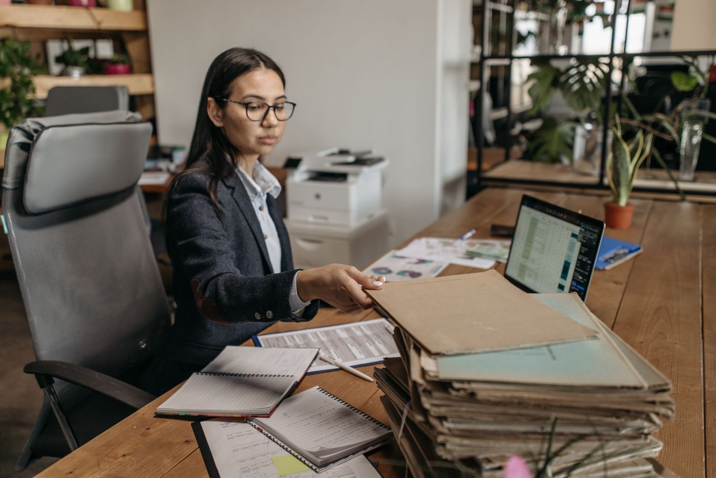 A case officer working through a stack of files at her desk