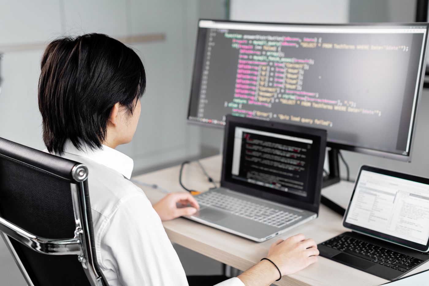 An engineer writing code at a desk with several screens